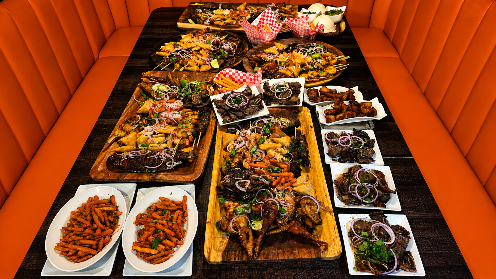 A long communal table set with Swahili platters, rice, greens and grilled meats